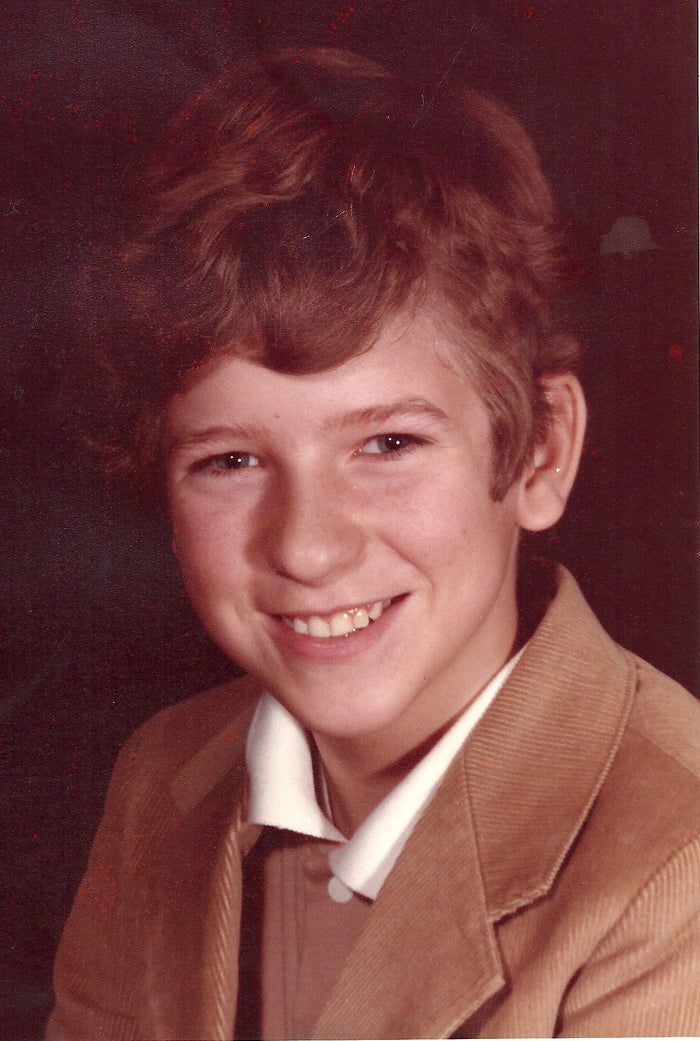 Portrait of Arthur Mills (Ray) in 1985, smiling in a tan corduroy jacket and white collar.
